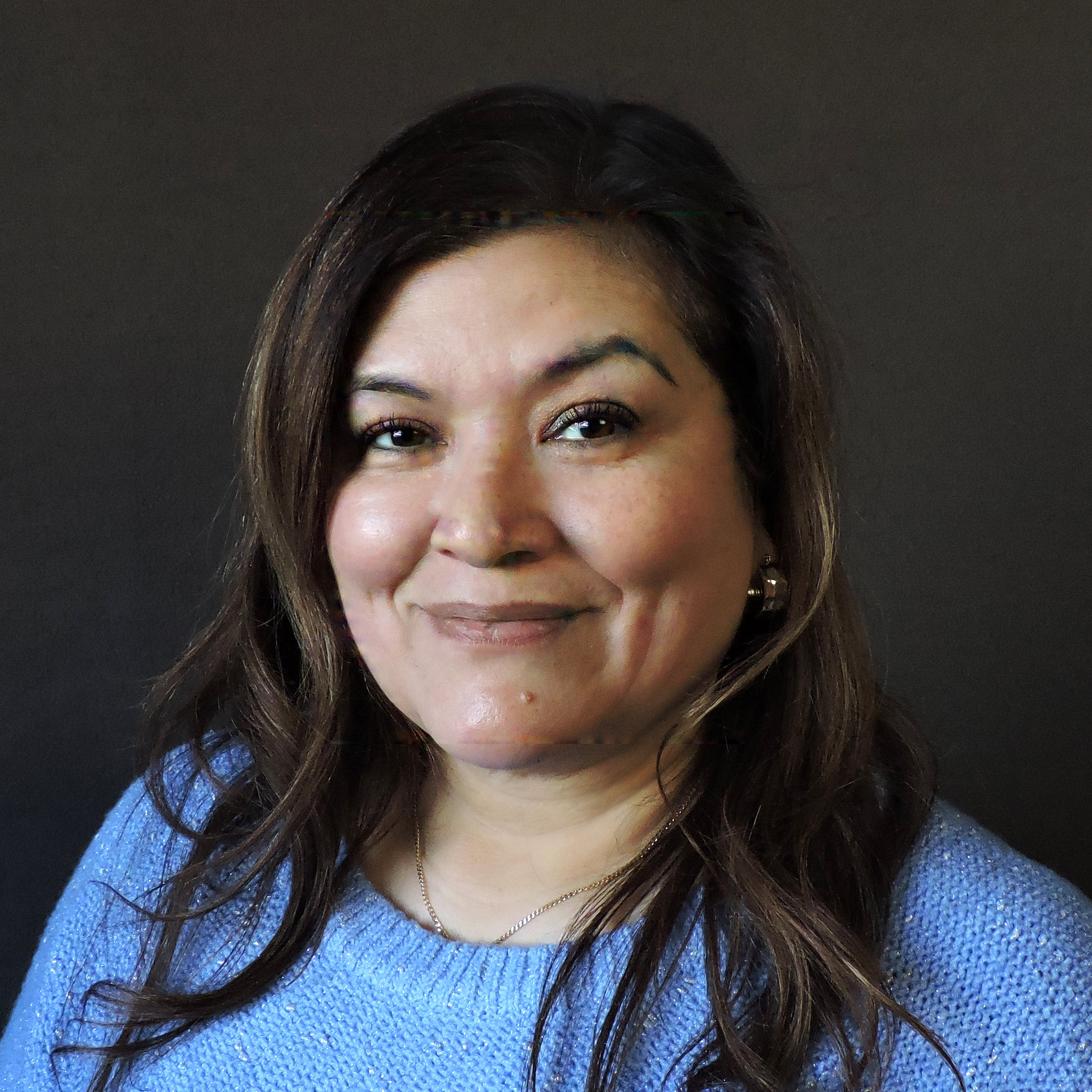 Laura Arias smiling in a blue sweater