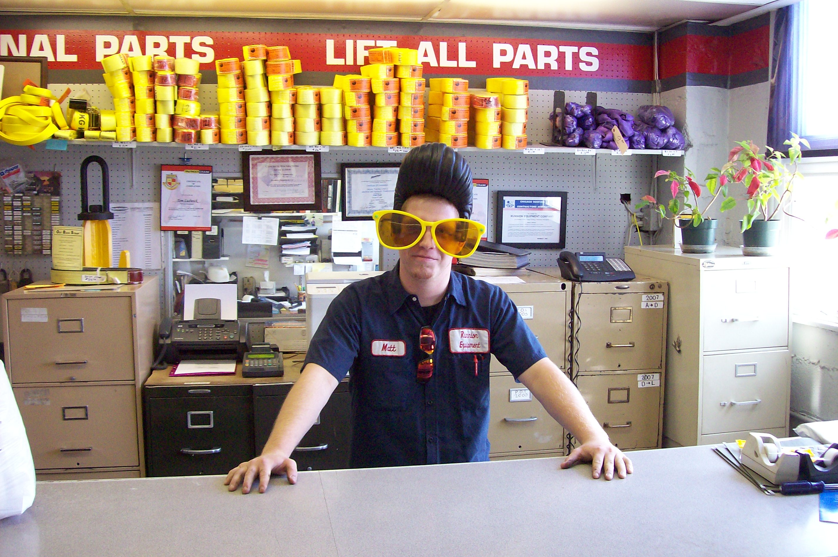 Matt Prochot wearing large yellow clown glasses at the parts department counter